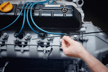 Close-up of an auto mechanic smiling repairing a lorry engine or a bus checking oil, concept repair in a garage, body shop.