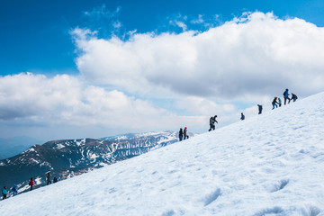 Hiking tourists climbs to the snow-capped mountain top. Concept theme: nature, weather, climbing,...