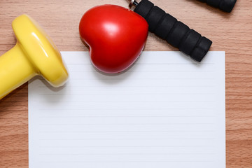 White line paper with sport equipment  on brown wooden table, top view