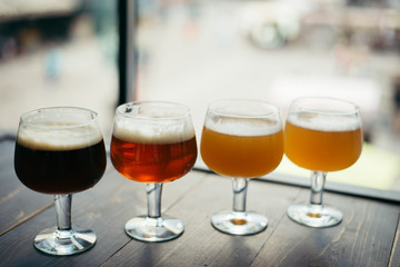four glasses of beer on wooden table