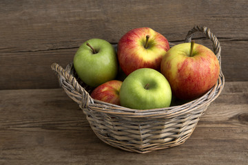 Basket of fresh apples on wooden background