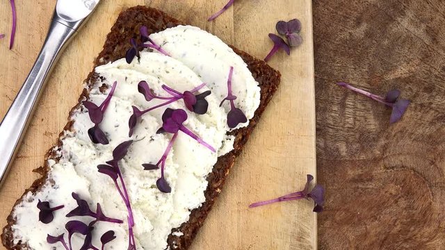 Cream Cheese and Cress on a slice of Bread (rotating on a wooden plate; seamless loopable; 4K)