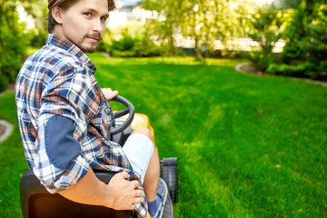 Young gardener man mowing the grass