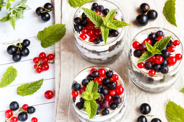 A sweet dessert of sponge cake with cream in a glass with fresh berries on wooden background