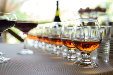 Row of glasses with whiskey or cognac on the table, free space. Strong alcohol in bar or...
