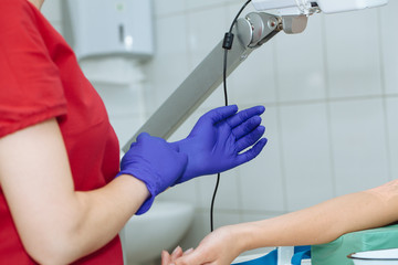 Obraz premium Crop image of nurse putting on blue medical glove for blood sampling