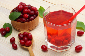 dogwood berries in wooden bowl with dogwood juice on white wooden table