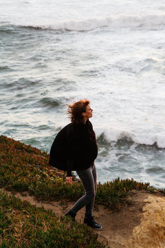 lifestyle image of young female woman exploring windy coast pacific ocean