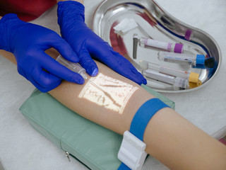Nurse taking blood for analysis via veins projector device