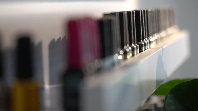 Jars with varnish for manicure gently stand in a row on a white shelf