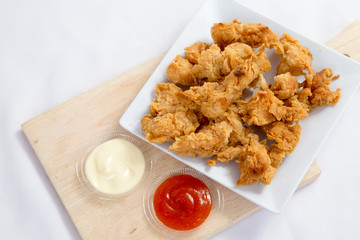 Fried crispy chicken breaded with corn flake crumbs with ketchup on wooden board.