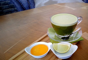 Matcha green tea on a glass cup on a wooden table.