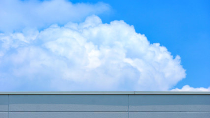 Fototapeta premium concrete wall of high building with blurred cloud and blue sky as background