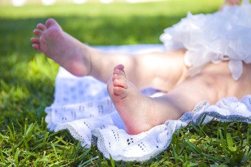 Close-up of the little baby legs on a green grass