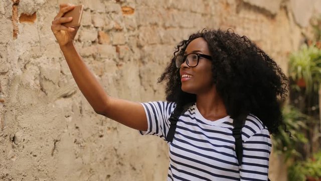 Portrait of young attractive woman taking photo of the ancient city using smart phone.