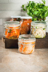 Concept of a fermented meal. Home canned food and billets. Vegan food. Vegetables. Cans of canned salsa, sauerkraut, marinated carrots, kimchi and cauliflower broccoli. Home kitchen table. copy space