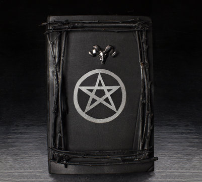 Black magic book with pentagram symbol and ram's head on