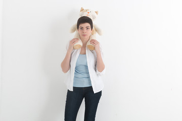 Young smiling woman in white shirt and jeans with short hair who is carrying plush toy cat on her shoulders.