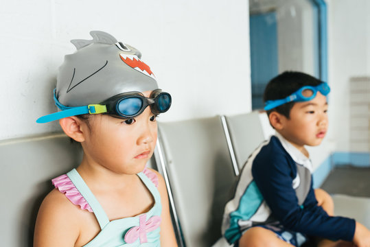 Asian American fraternal twins waiting for swim lessons