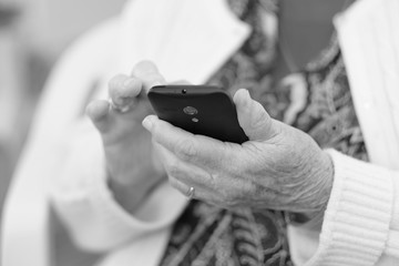 An elderly woman is holding a phone and studying his work