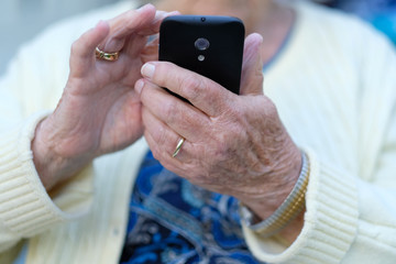 Wrinkled hands of an elderly woman with a mobile phone