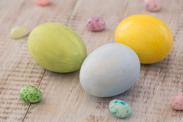 Pastel Painted Easter Eggs and Jelly Beans on White Wood Background