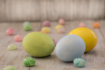 Pastel Painted Easter Eggs and Jelly Beans on Wood Background