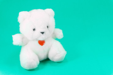 Lovely white teddy bear toy sitting with red heart on green background, fall in love teddy bear,toy for children