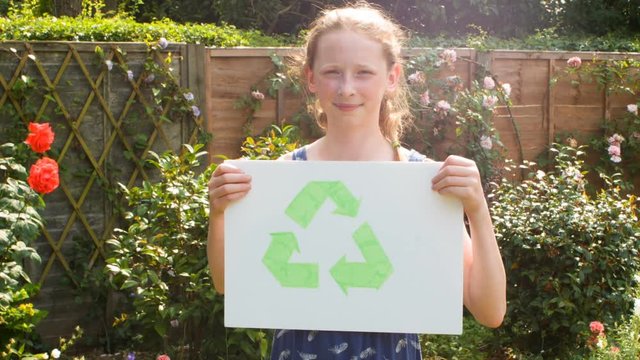 Pre teen caucasian girl holding a placard of the recycling symbol themes of environmental conservation symbol recycling protection
