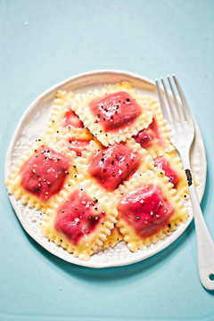 Beetroot ravioli with olive oil on blue surface