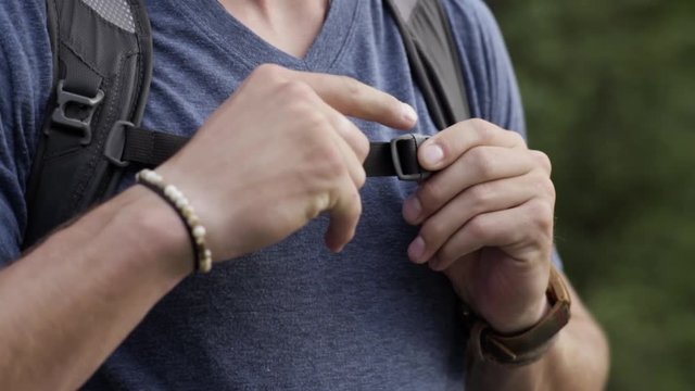 Closeup Of Hiker Buckling His Chest Strap On His Backpack, He Tightens It, And Walks Away