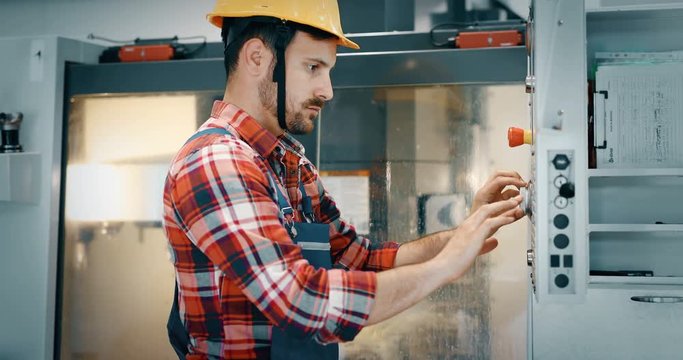 Industry Worker entering data in CNC machine at factory