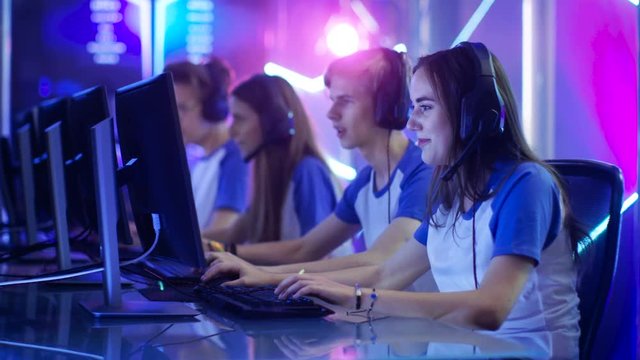 Team of Teenage Gamers Get Ready for eSport Tournament, Put on Their Headsets. Tournament Area/ Internet Cafe Looks Cool with Neon Lights. Shot on RED EPIC-W 8K Helium Cinema Camera.