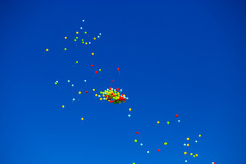 Group of multicolored helium filled balloons in the blue sky