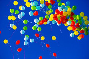 Group of multicolored helium filled balloons in the blue sky