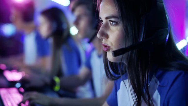 Beautiful Professional Gamer Girl and Her Team Participate in eSport Cyber Games Tournament. She Has Her Headphones and as a Team Leader She Commands Strategical Maneuvers into Microphone. 