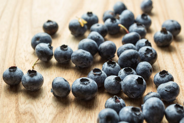 Ripe spilled blueberries on a wooden table.