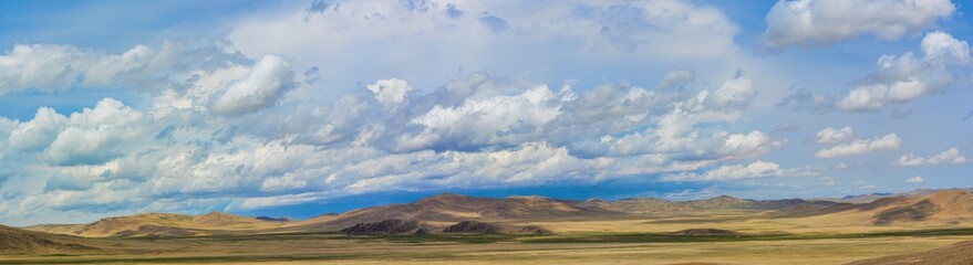 fluffy rainy clouds over green hills at sunny day  
