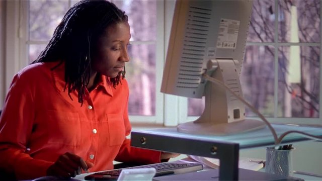 Medium shot of African American woman working with flatscreen computer.