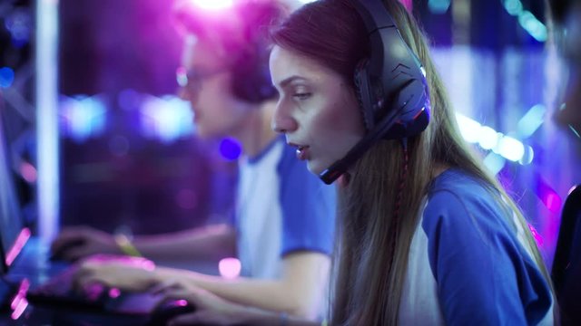 Beautiful Professional Gamer Girl and Her Team Participate in eSport Cyber Games Tournament. She Has Her Headphones and Talks into Microphone. Shot on RED EPIC-W 8K Helium Cinema Camera.