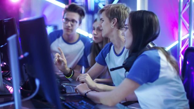 Team of Professional Boys and Girls Gamers Actively Thinking/ Discussing Game Strategy/ Tactic, They're In Internet Cafe or on Cyber Games Tournament. Shot on RED EPIC-W 8K Helium Cinema Camera.
