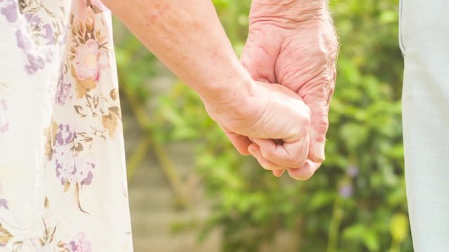 Low angle view of an affectionate Senior Caucasian couple holding hands in their garden themes of love togetherness retirement romantic
