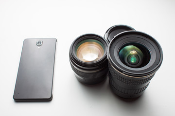 close-up of group of camera lenses and a mobile phone on a white
