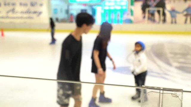 Blur image of couple and Pretty little girl playing ice skate in stadium rink.Blurry view interior people play ice-skating