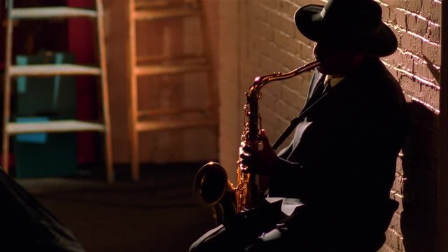 Legendary African-American sax player plays against old brick wall.