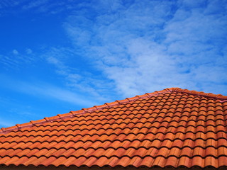 Orange cement tile pyramid like roof, with blue sky and fade distributed white cloud background