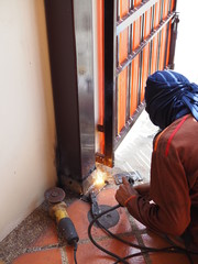 Worker repairing old iron column at gate corner of the house, sparking welding