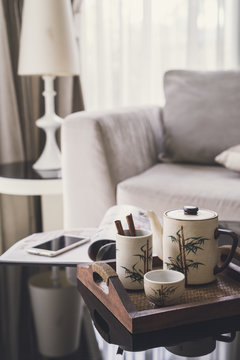 cup of tea on wooden tray on a round table with sofa in living room