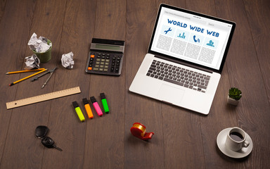 Laptop on wooden desk with office suplies