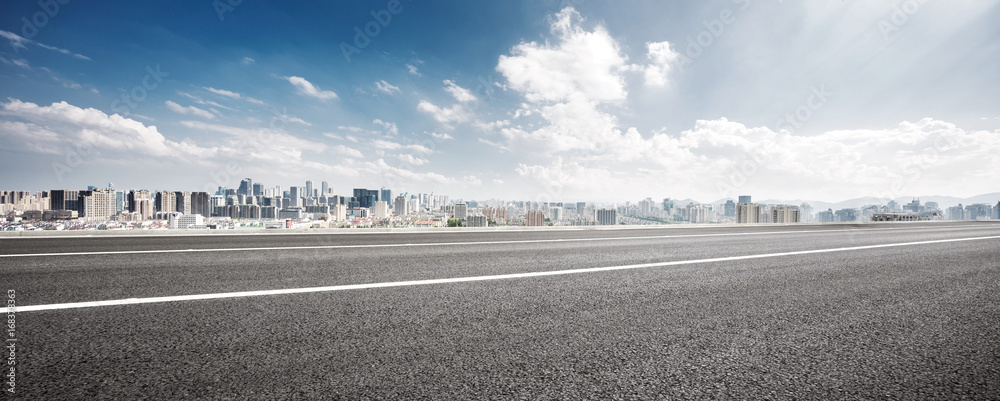 Wall mural empty road and cityscape of modern city against cloud sky - Wall murals